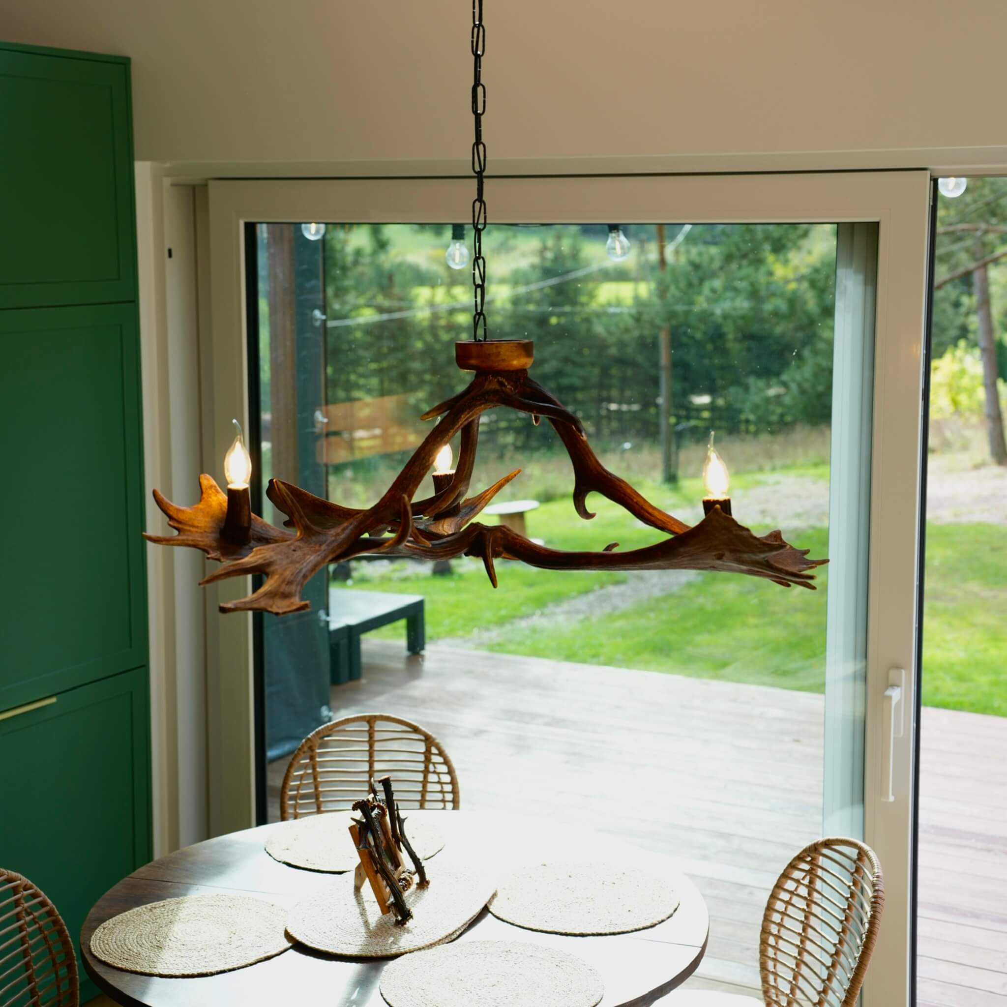 Three-light low chandelier made from genuine antlers, providing a warm and inviting glow.